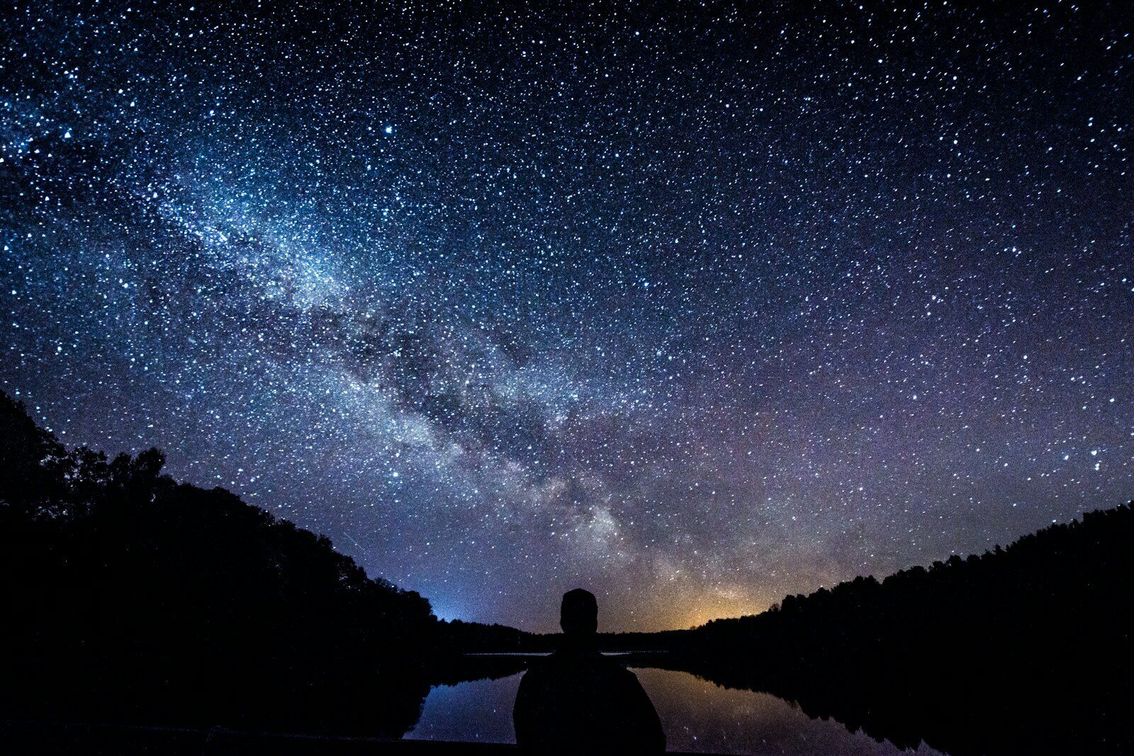 silhouette of person standing under starry sky